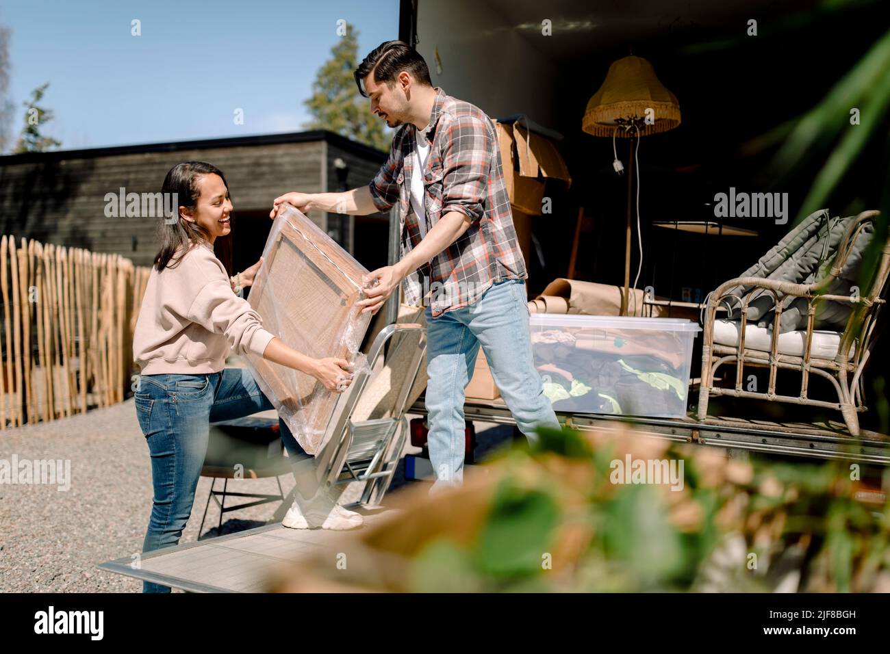 Uomo e donna che scaricano la pittura dal camion durante la giornata di sole Foto Stock
