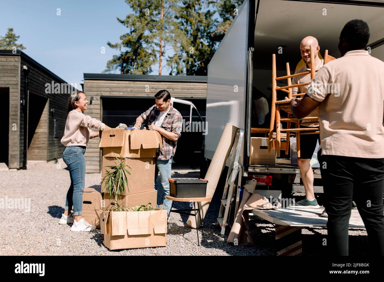 I professionisti che trasportano le sedie dal camion mentre la coppia osserva attraverso le scatole Foto Stock