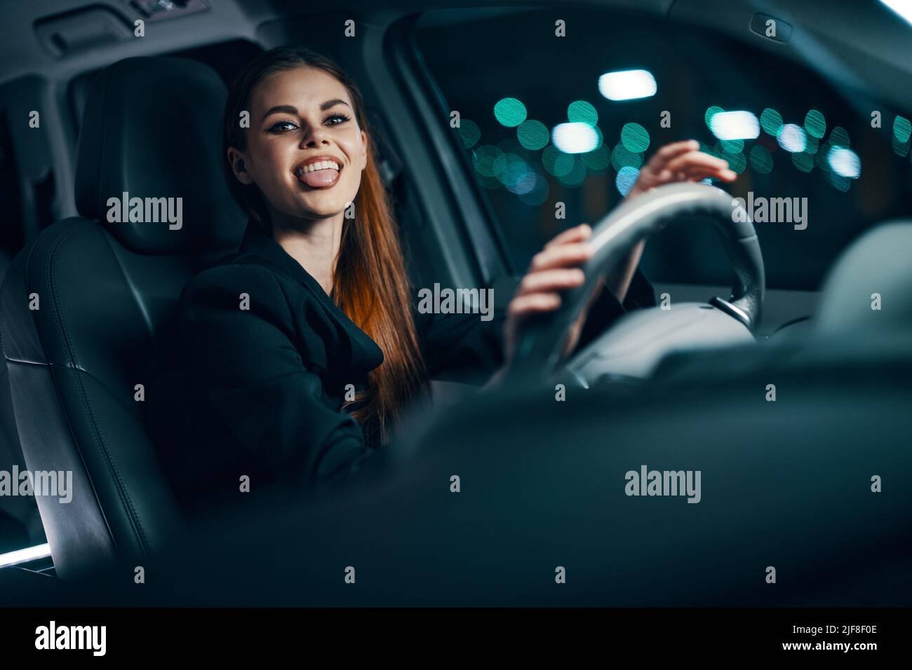 foto orizzontale di una donna divertente e rilassata seduta al volante di  un'auto con una cintura di sicurezza allacciata, sorridendo piacevolmente  mostrando la lingua al Foto stock - Alamy