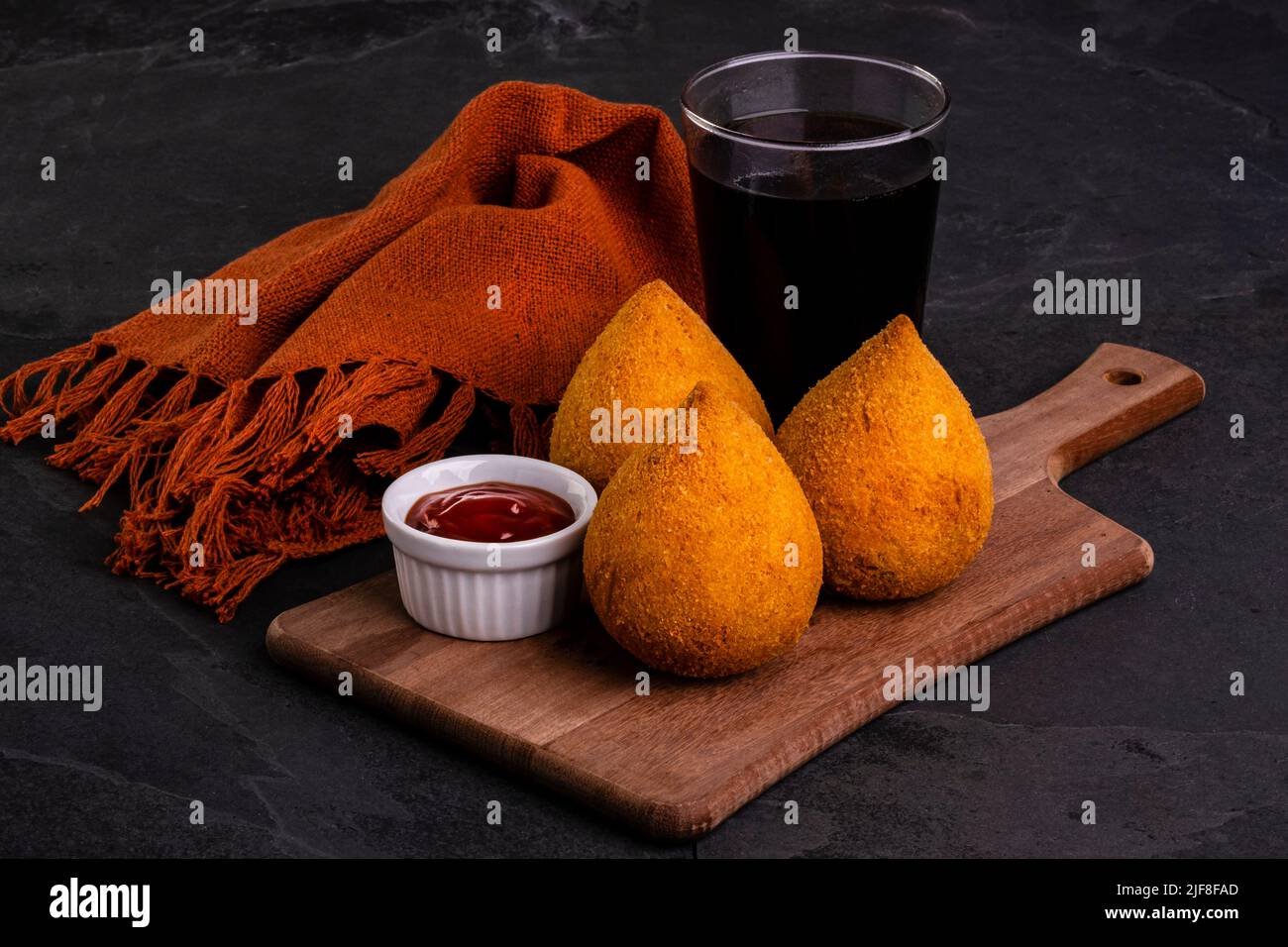 Tradizionale coxinha fritto ripieno di pollo e un bicchiere di soda fredda. Foto Stock