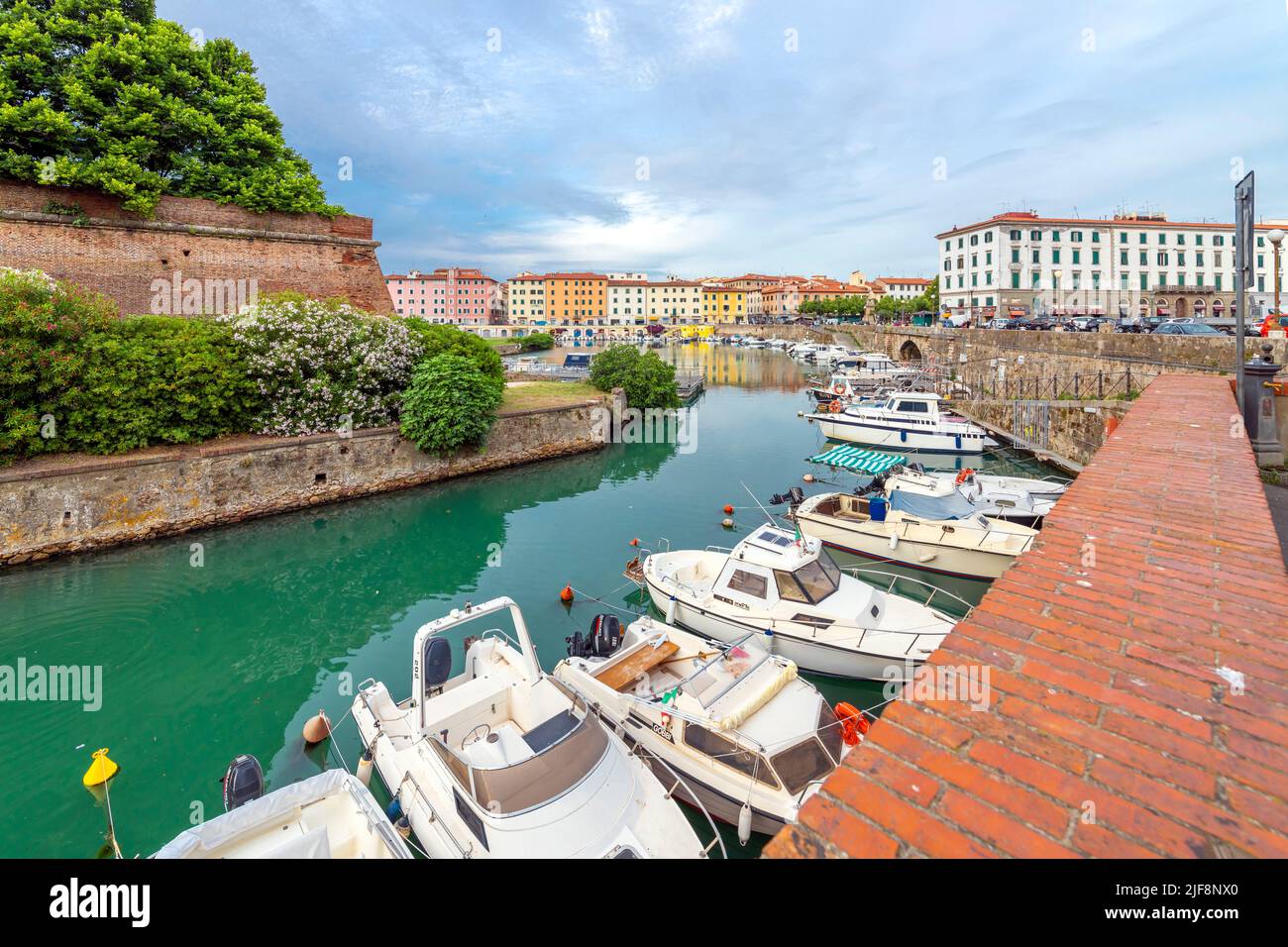 Le barche costeggiano gli affollati canali accanto alla Nuova Fortezza e un caffè sul lungomare all'aperto presso la città toscana di Livorno, Italia. Foto Stock