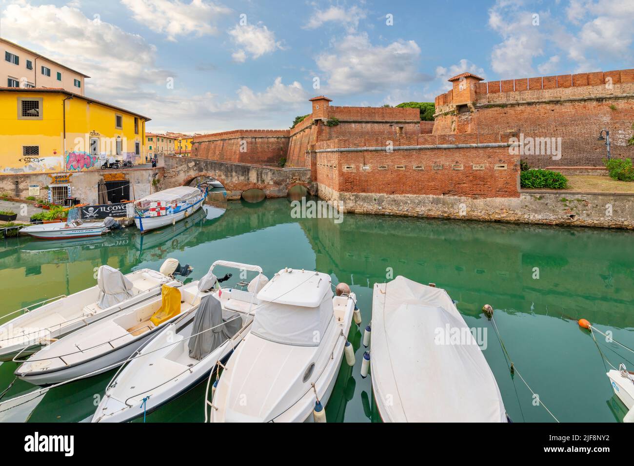 Le barche costeggiano gli affollati canali accanto alla Nuova Fortezza e un caffè sul lungomare all'aperto presso la città toscana di Livorno, Italia. Foto Stock