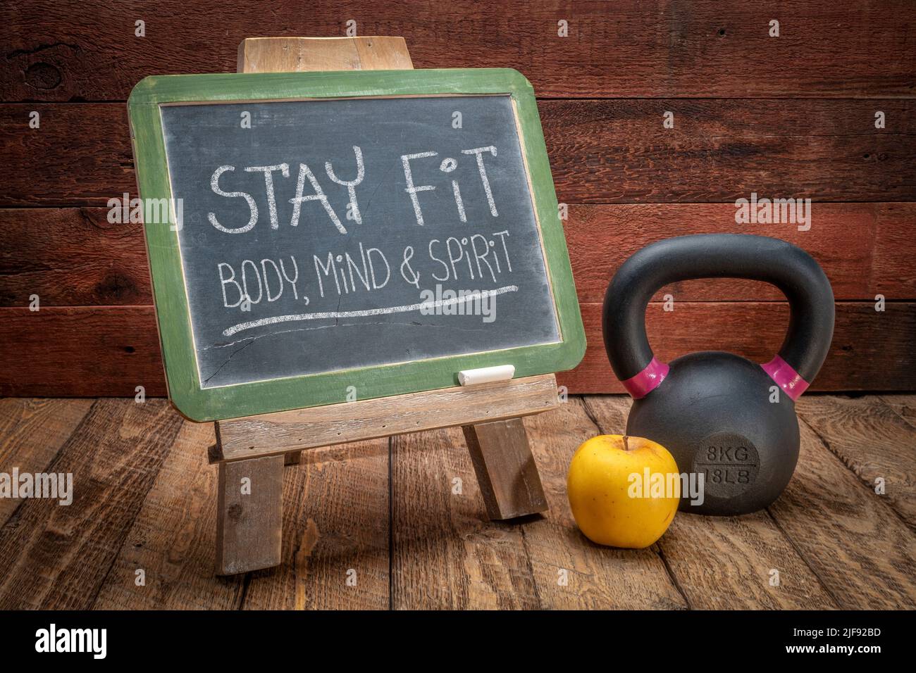 restate in forma, corpo, mente e spirito segno - ispirato gesso scrittura su una lavagna ardesia con un kettlebell e mela, fitness e sviluppo personale Foto Stock