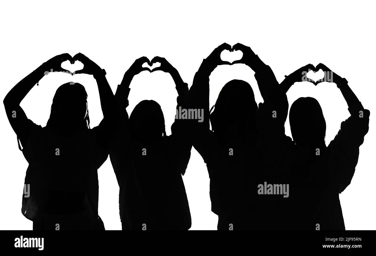 Quattro figure femminili in bianco e nero a contrasto elevato, che fanno dei simboli a forma di cuore dell'amore con le mani sopra la testa. Foto Stock