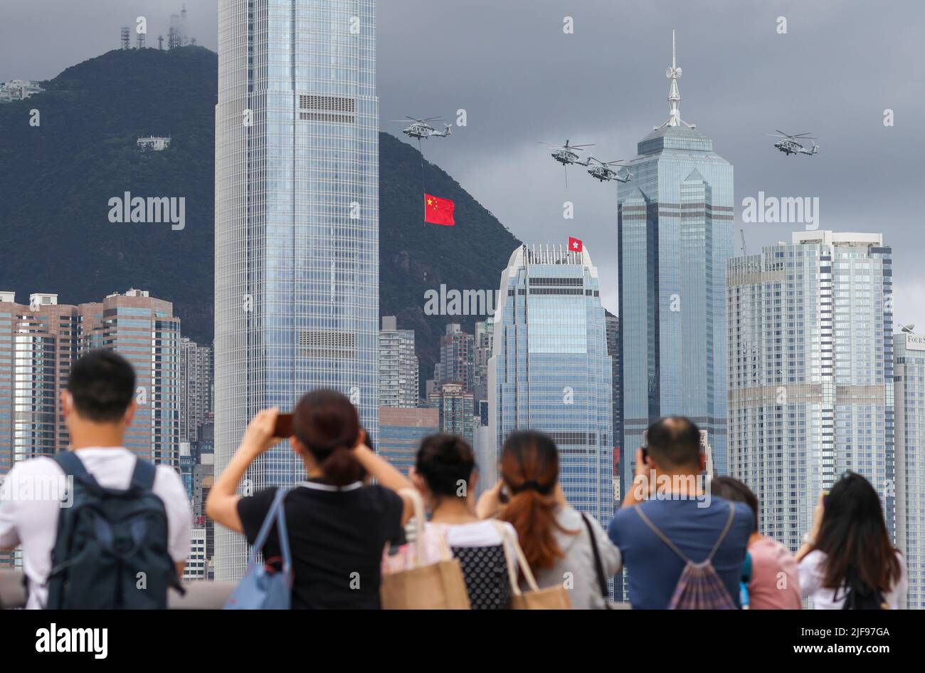 Hong Kong, Cina. 01st luglio 2022. 1st luglio, Hong Kong. I membri del pubblico guardano gli elicotteri del Governo Flying Services che trasportano le bandiere nazionali e SAR sorvolano e sfilano in mare durante la cerimonia di sollevamento della bandiera a Piazza Golden Bauhinia a WAN Chai per celebrare il 25th° anniversario dell'istituzione della HKSAR, guardando dal lungomare di Tsim Sha Tsui, mentre la polizia pattuglia e stare in piedi guardia. 01JUL22 SCMP/Nora Tam Credit: South China Morning Post/Alamy Live News Foto Stock