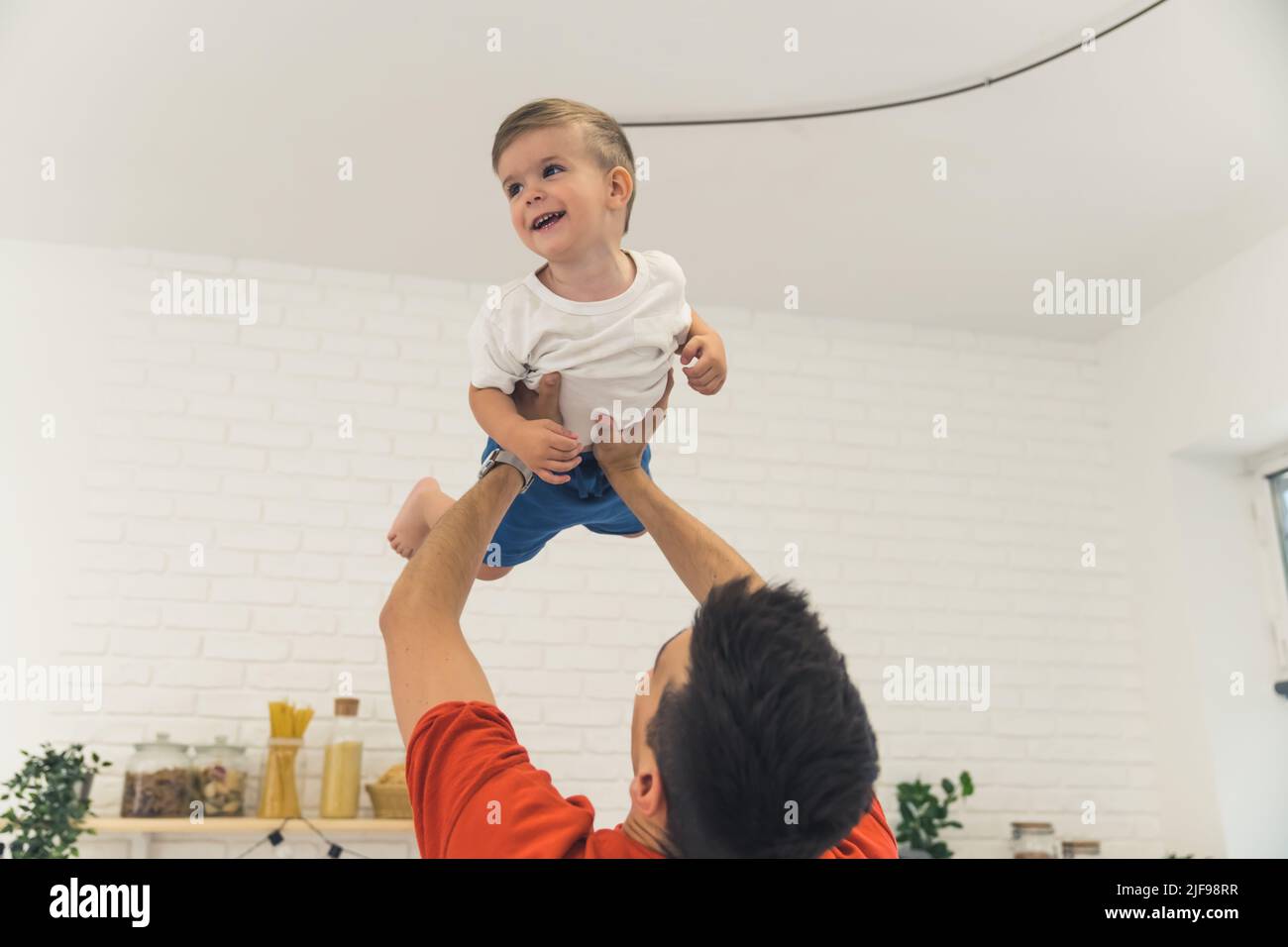 padre che tiene in mano il suo bel figlio a casa, felice concetto di famiglia. Foto di alta qualità Foto Stock