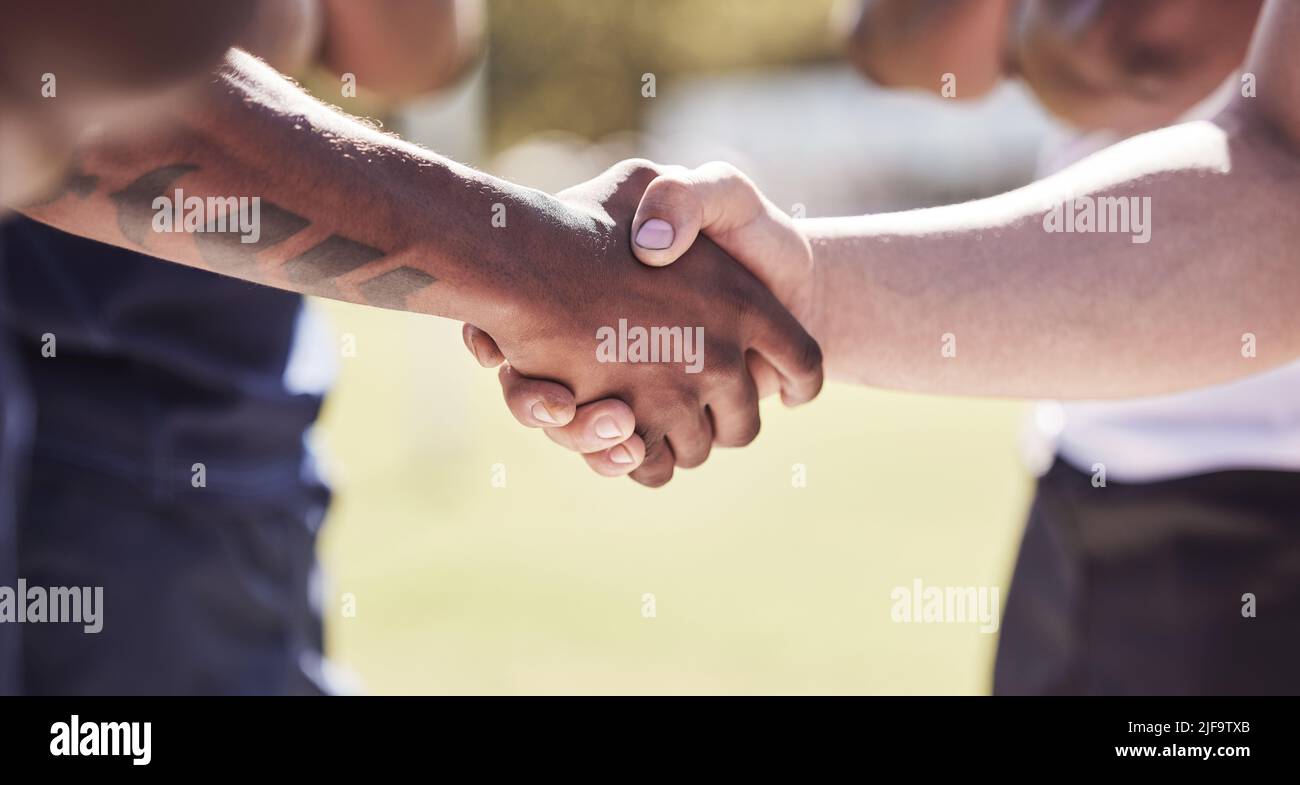 Primo piano due squadre di rugby avversari che scuotono le mani prima o dopo una partita fuori su un campo. I giocatori di Rugby condividono una stretta di mano per mostrare rispetto e. Foto Stock