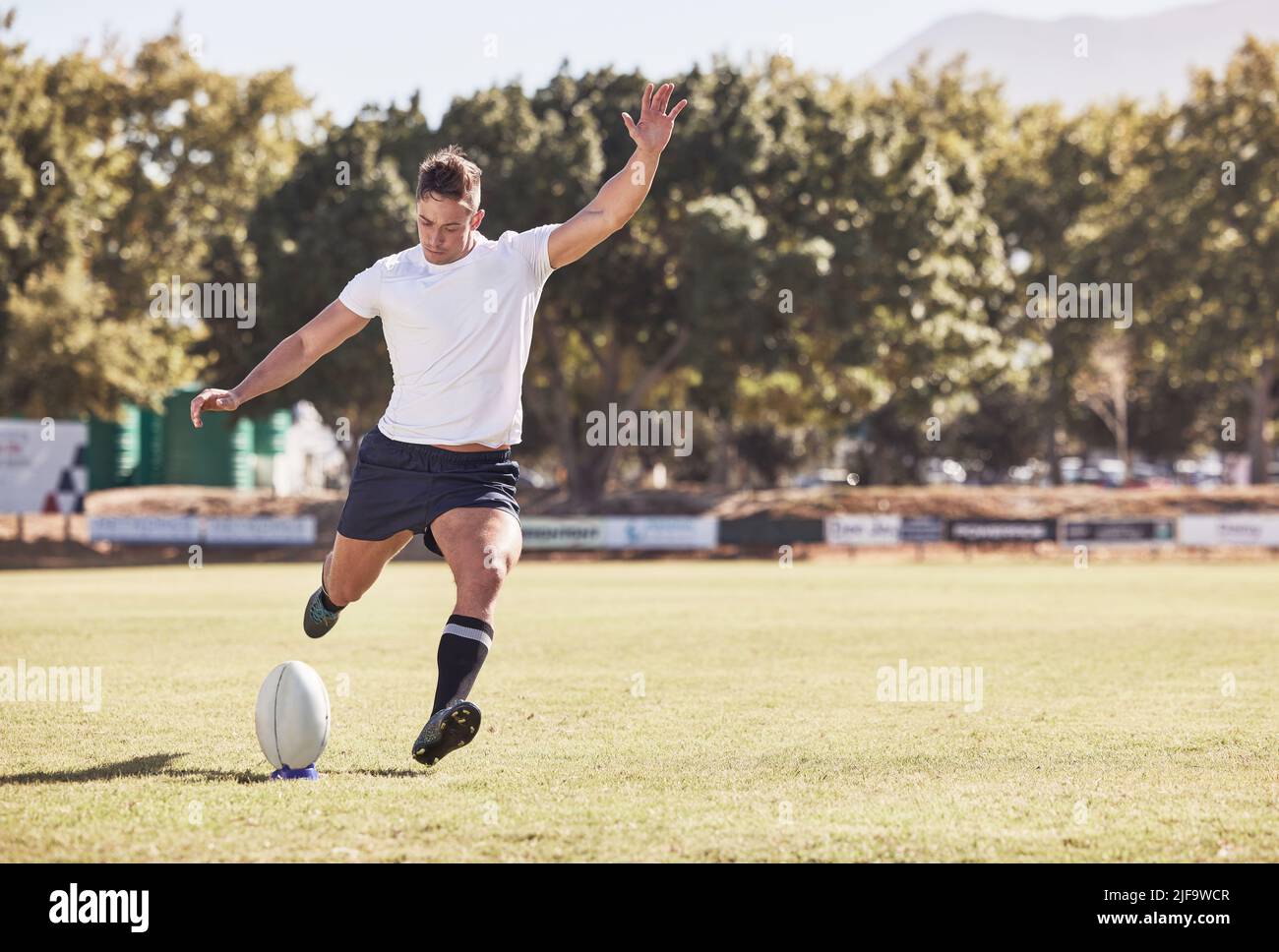 Un giocatore di rugby caucasico che ha calci fuori durante una partita di rugby fuori sul campo. Giovane atletico che prende una penalità o tenta di segnare un Foto Stock