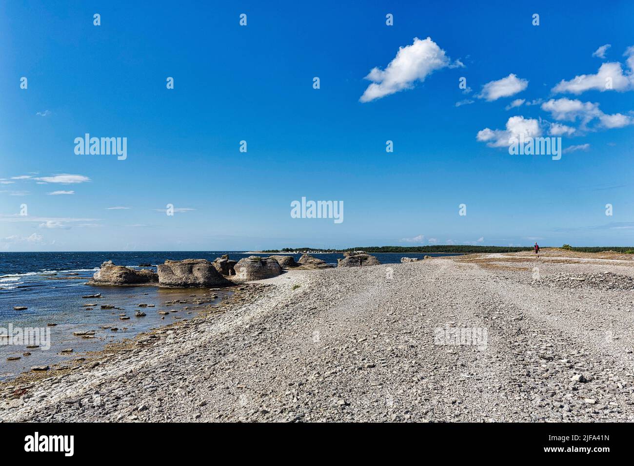 Spiaggia di pietra con Raukar e vista del bacino del porto precedente Gamle Hamn o Gamla hamn, escursionisti all'orizzonte, Faroe Island, Faroe, Gotland, Baltico Foto Stock