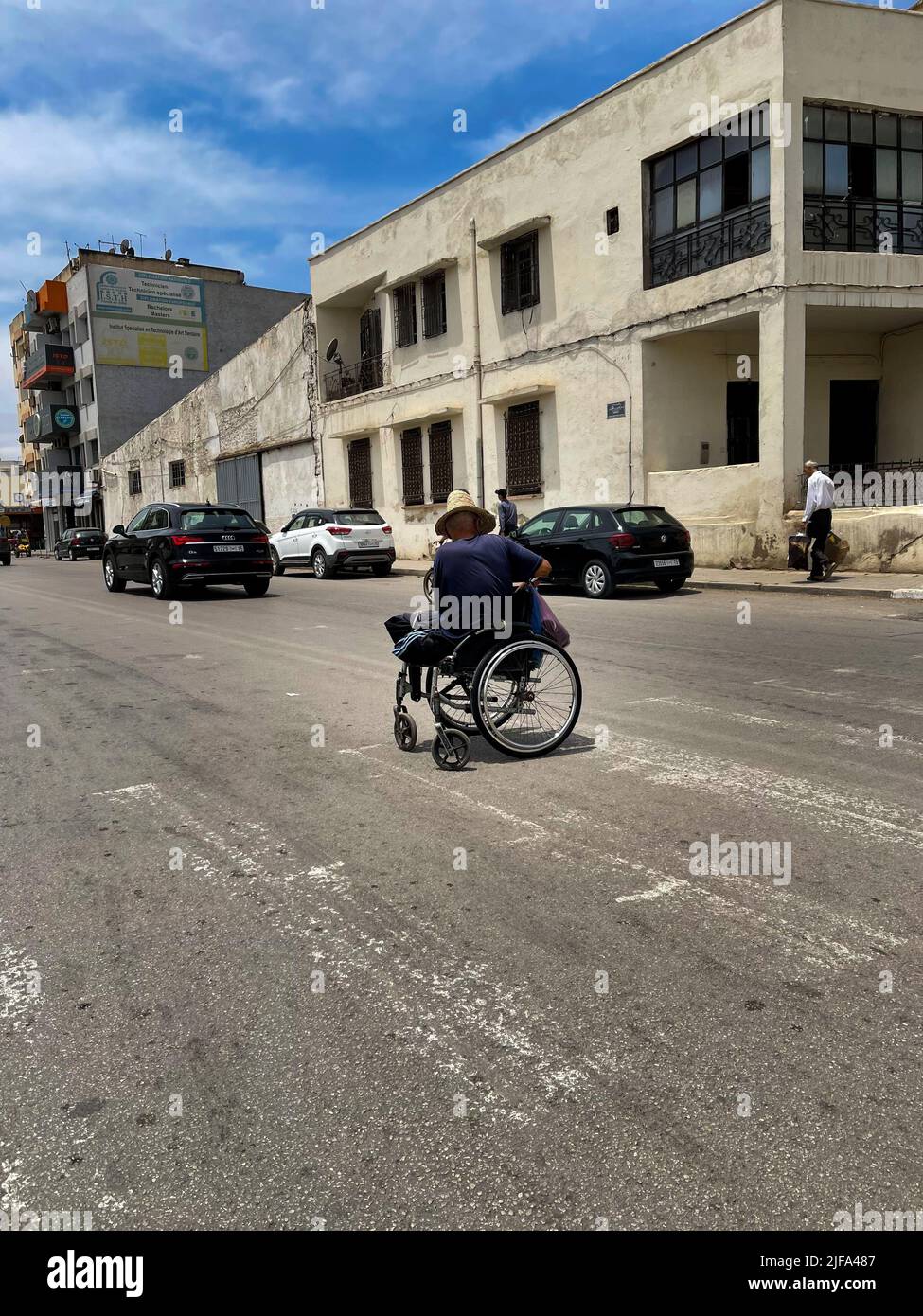 Un adulto disabili in una sedia a rotelle si begn per soldi nel mezzo della strada Foto Stock