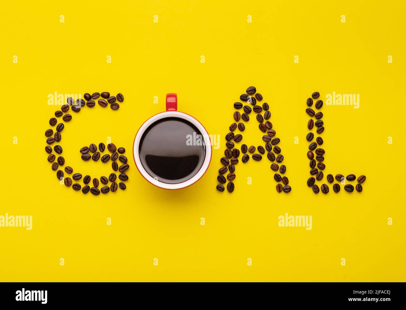 Vista dall'alto di Americano in tazza rossa e chicchi di caffè incantano il GOL parola su sfondo giallo Foto Stock
