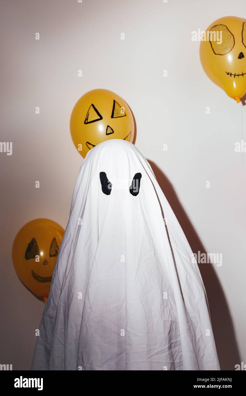 Buon Halloween. Uomo in abito bianco fantasma e palline arancioni dipinte. Emozioni diverse di gioia, rabbia, risate. Design festivo, concetto di festa. Foto Stock