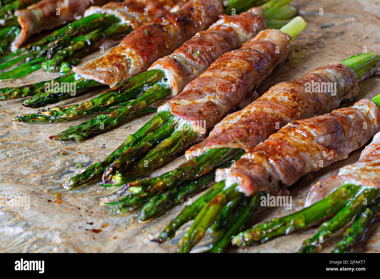 Asparagi verdi al forno avvolti in pancetta croccante. Spuntino leggero, contorno (guarnitura). Foto Stock