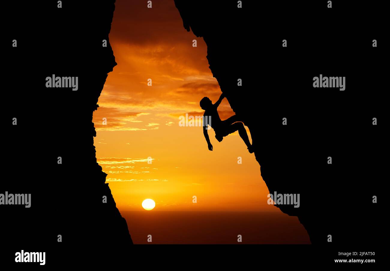 Irriconoscibile adrenalina junkie che fa sport estremi. Uomo sconosciuto che fa scalata di montagna al tramonto. Dark shot di un giovane maschio appassionato di suo Foto Stock