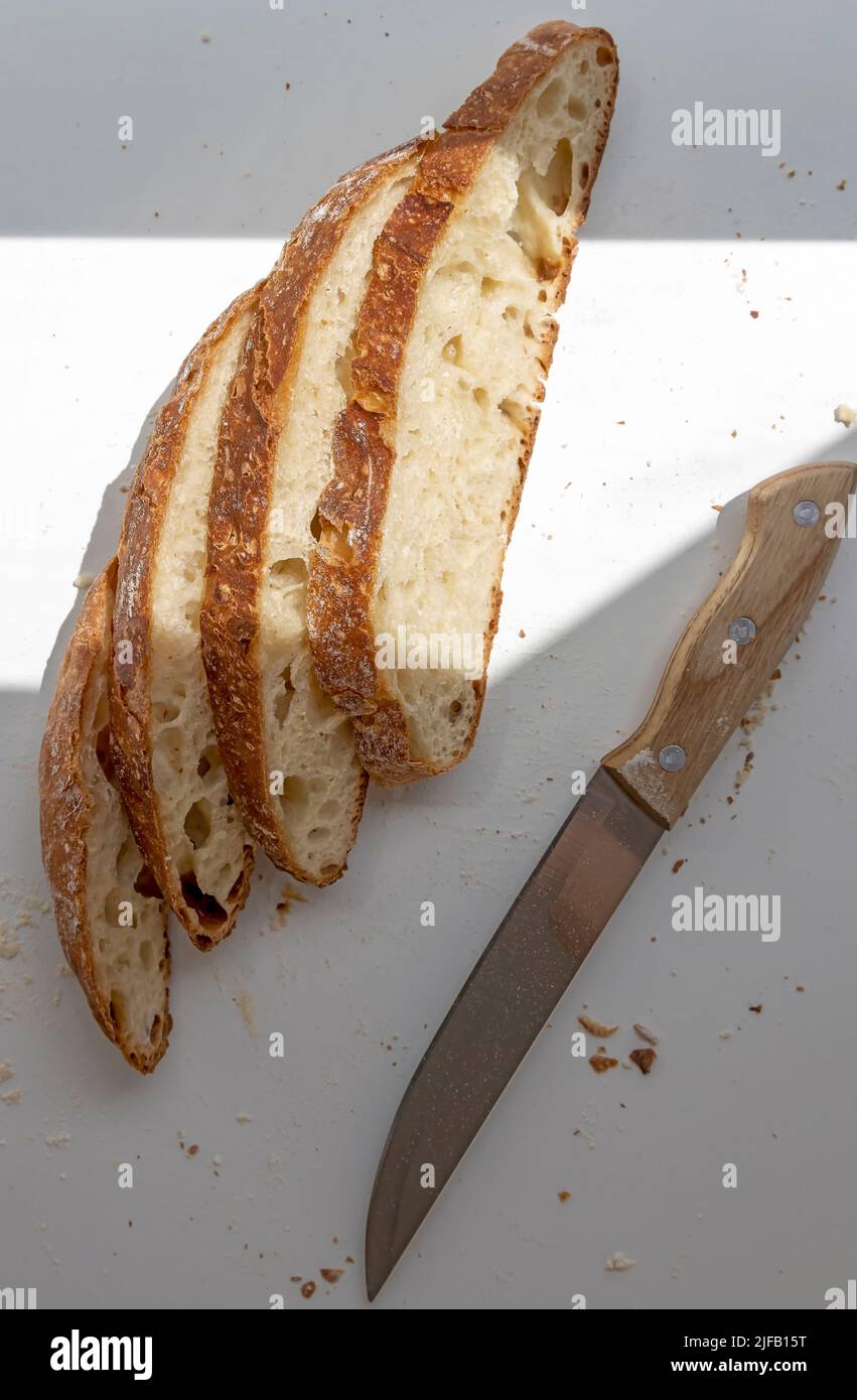 Pane bianco a fette e un coltello. Quattro fette di pane affettato. Vista dall'alto Foto Stock