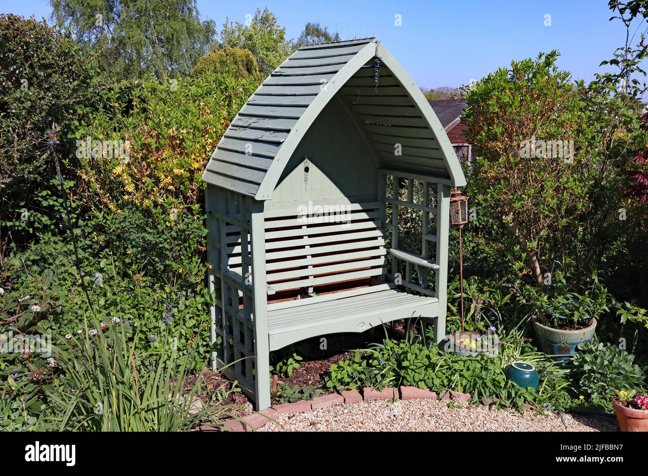Un arco di legno verde in un giardino all'inglese. Il luogo perfetto per riposarsi dopo una dura giornata di lavoro. Foto Stock
