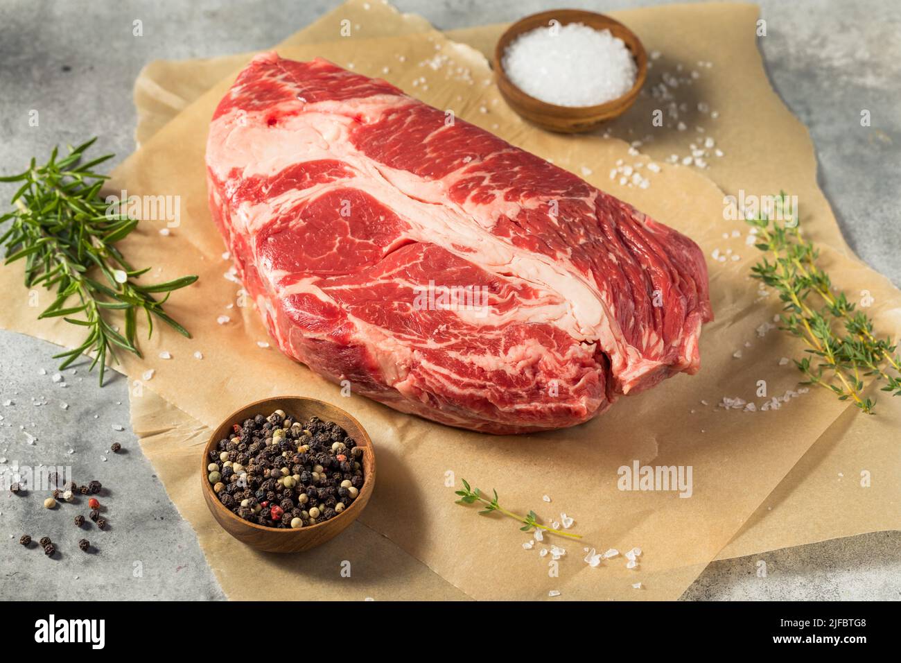Erba biologica cruda alimentato Chuck Roast con sale e pepe Foto Stock