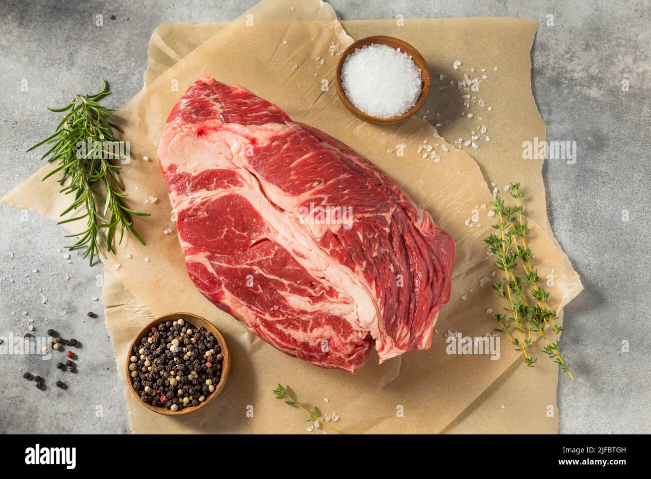 Erba biologica cruda alimentato Chuck Roast con sale e pepe Foto Stock