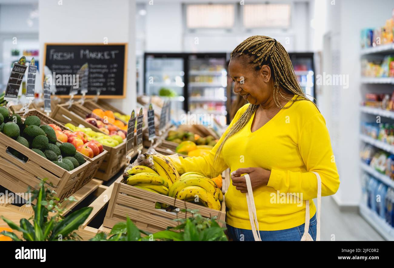 Donna africana anziana che acquista frutta fresca in supermercato Foto Stock