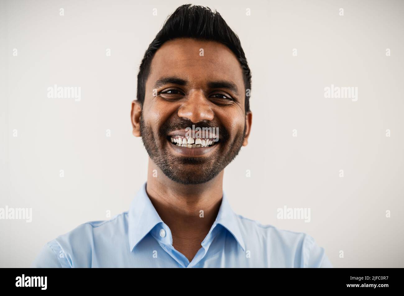 Uomo indiano felice di affari che sorride in macchina fotografica all'interno dell'ufficio Foto Stock