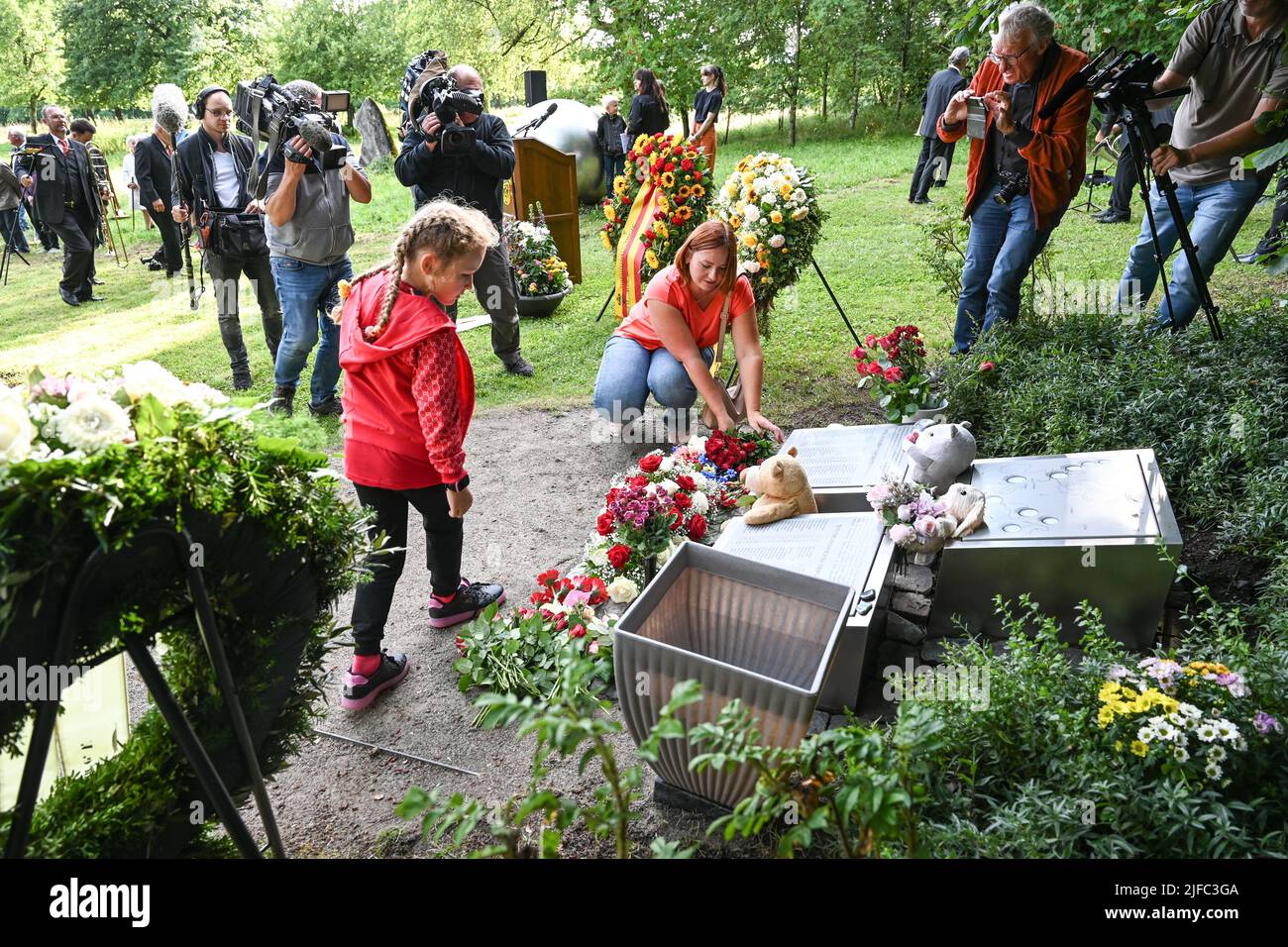 Baden Wuerttemberg, Germania. 01st luglio 2022. 01 luglio 2022, Baden-Wuerttemberg, Brachenreuthe bei Überlingen: I parenti Ella Karimova (inginocchiati) e sua figlia Diana Karimov dalla Russia deposero fiori al memoriale. La sorella di Ella Karimova è stata uccisa 20 anni fa nel crollo dell'aereo. La collana di perle lacerate, come si chiama l'opera d'arte del memoriale, commemora l'incidente aereo il 1 luglio 2002 vicino a Überlingen. A quel tempo, 71 persone sono state uccise durante la collisione di due aerei. Foto: Felix Kästle/dpa Credit: dpa Picture Alliance/Alamy Live News Foto Stock