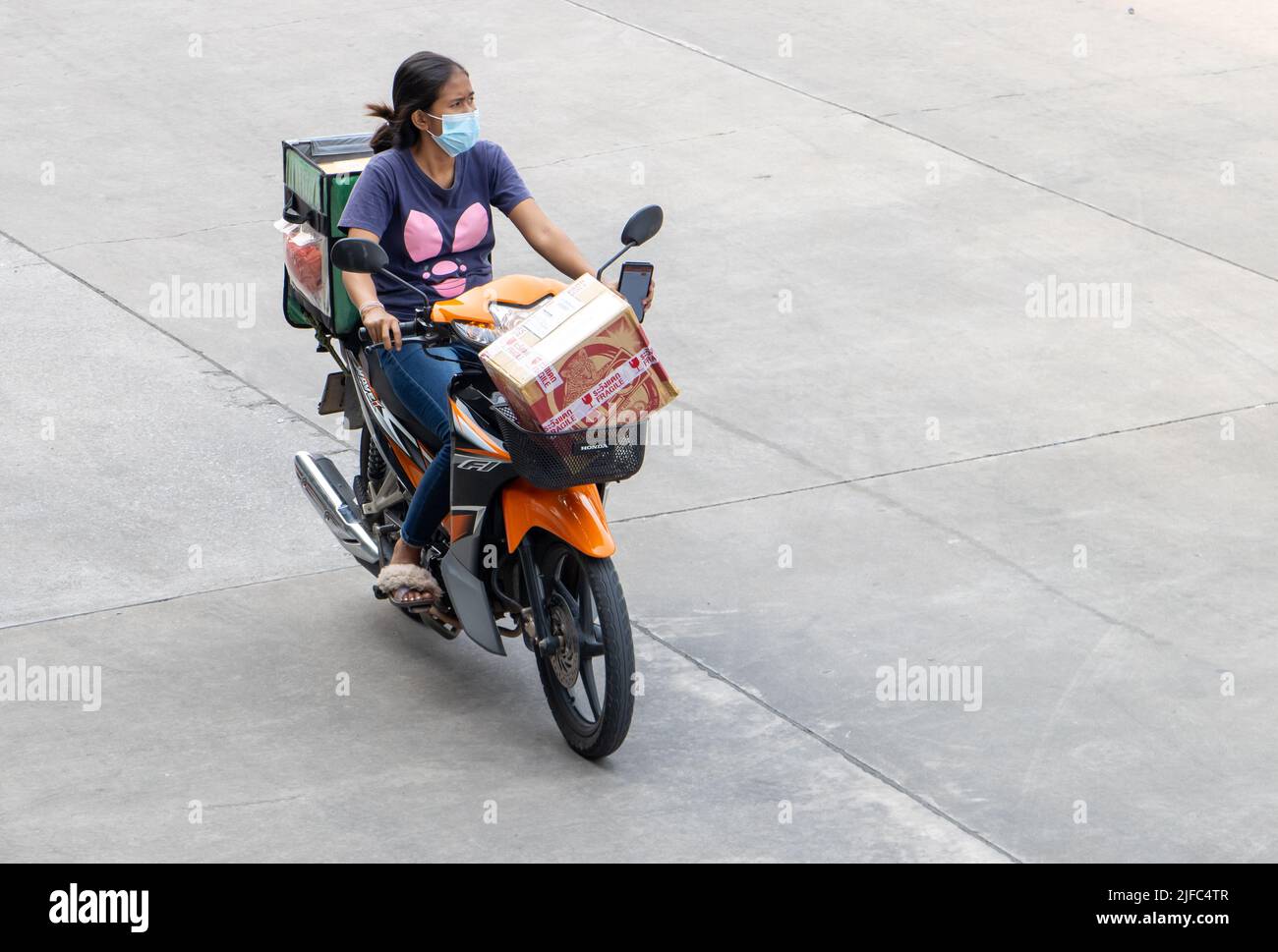 SAMUT PRAKAN, THAILANDIA, Apr 07 2022, Un addetto alle consegne guida una motocicletta con una spedizione Foto Stock