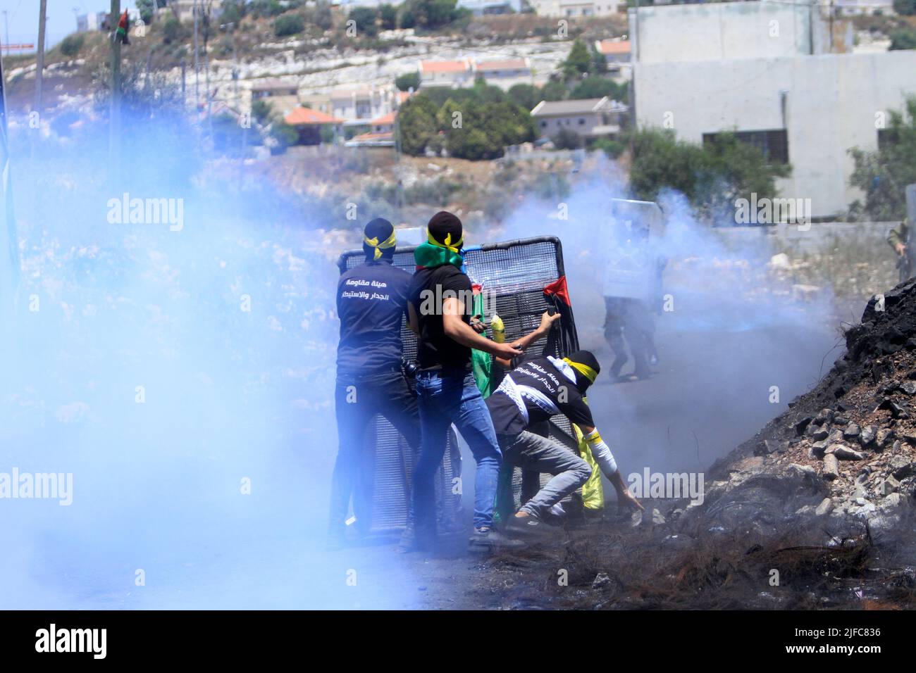 Nablus, Palestina. 01st luglio 2022. I manifestanti palestinesi lanciano pietre contro i soldati israeliani mentre si coprono dietro gli scudi mentre una granata stordita esplode durante una dimostrazione contro gli insediamenti israeliani nel villaggio di Kafr Qaddum vicino alla città di Nablus in Cisgiordania. Credit: SOPA Images Limited/Alamy Live News Foto Stock