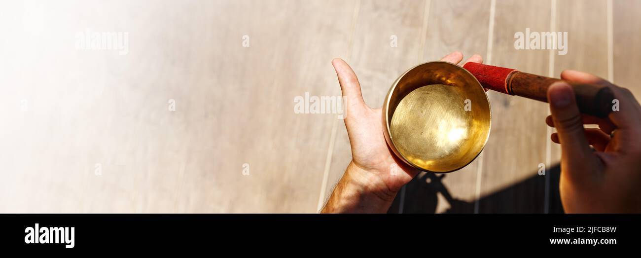 L'uomo mani usando la ciotola di canto nella terapia healing del suono all'aperto, la bandiera di primo piano Foto Stock