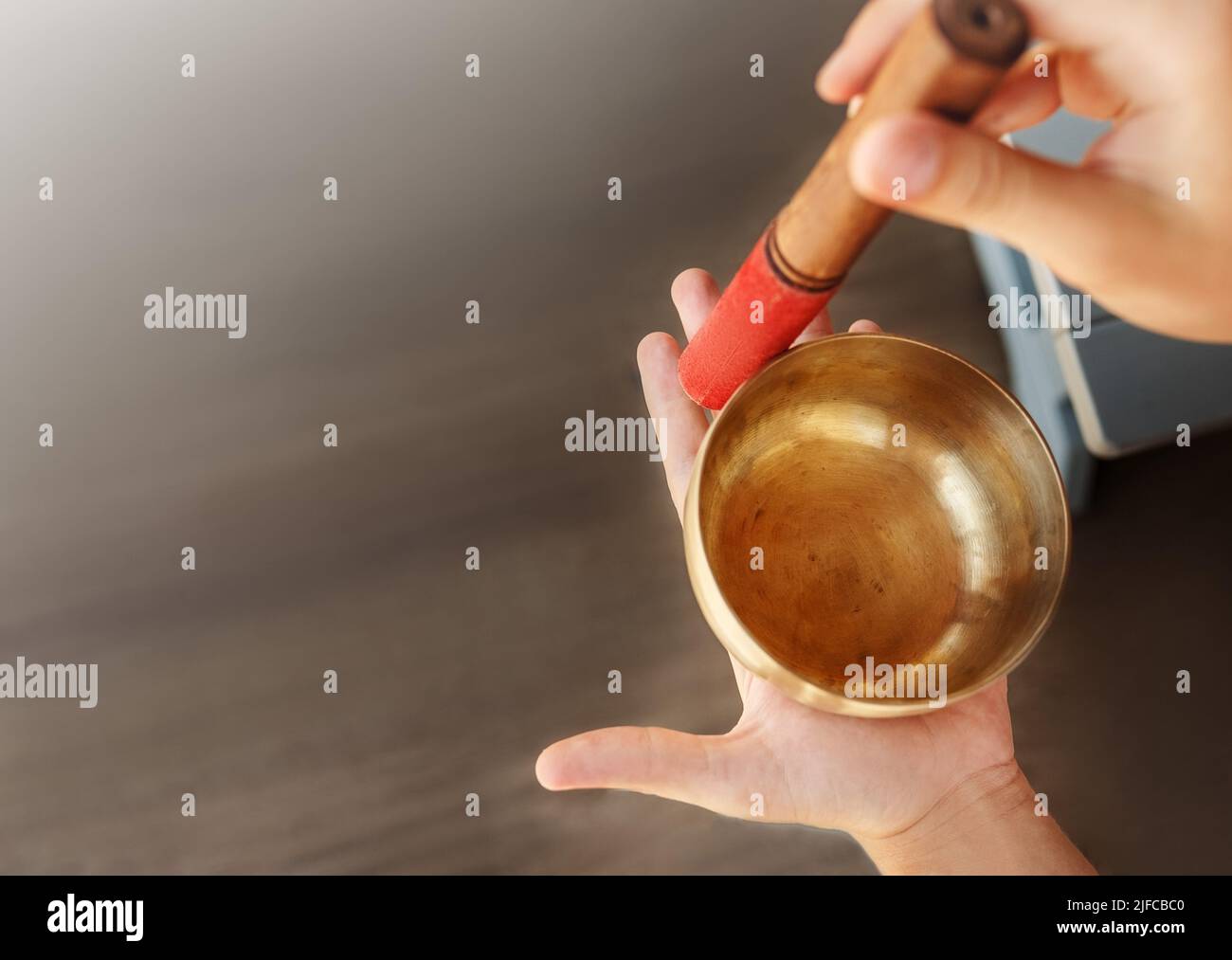 L'uomo mani usando la ciotola di canto nella terapia healing del suono all'aperto, primo piano. Foto Stock