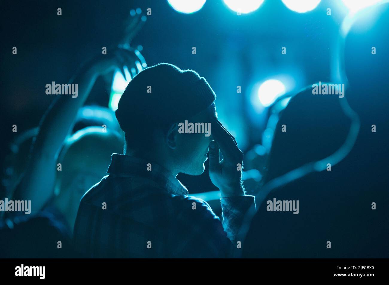 Una silhouette di un uomo a una festa sotto la luce blu Foto Stock