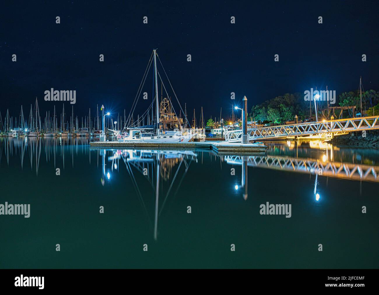Una vista notturna della Marina tropicale che riflette la barca e le luci del porto Foto Stock
