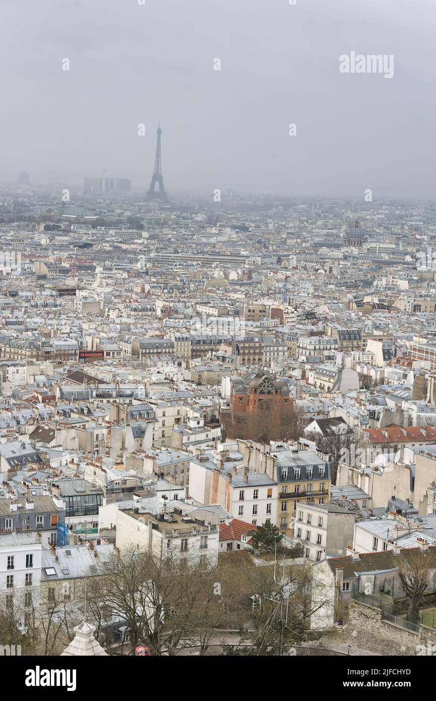 Uno scatto verticale aereo della famosa città di Parigi con la torre Eiffel in lontananza in una giornata di nebbia Foto Stock