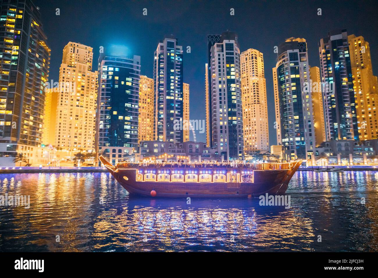 Barca turistica, Barca turistica vela a Dubai Marina di notte. La vista notturna degli alti edifici del Marina residenziale di Dubai e' il quartiere in Foto Stock