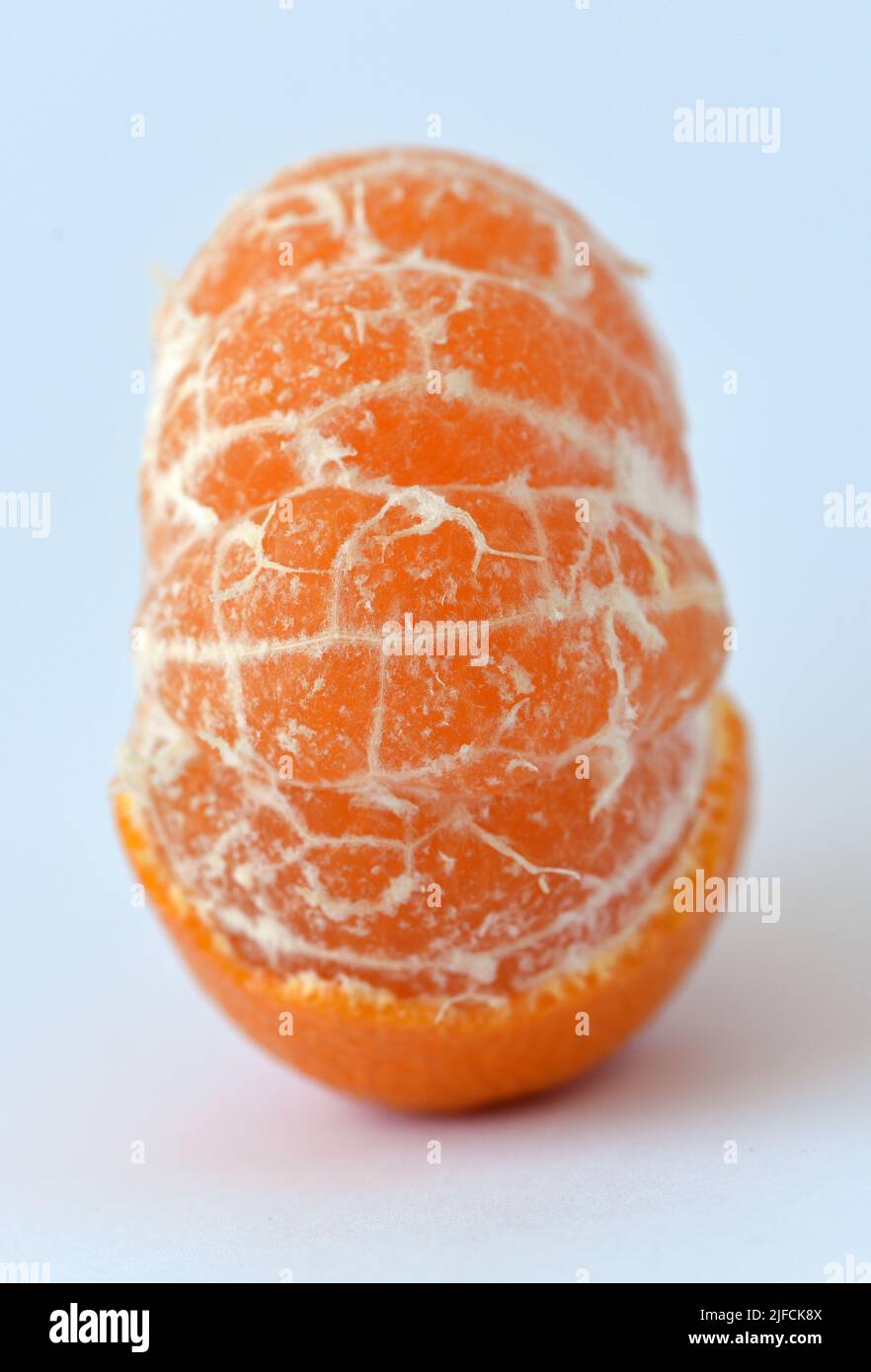 Una vista del lato di un frutto arancione parzialmente pelato con segmenti visibili Foto Stock