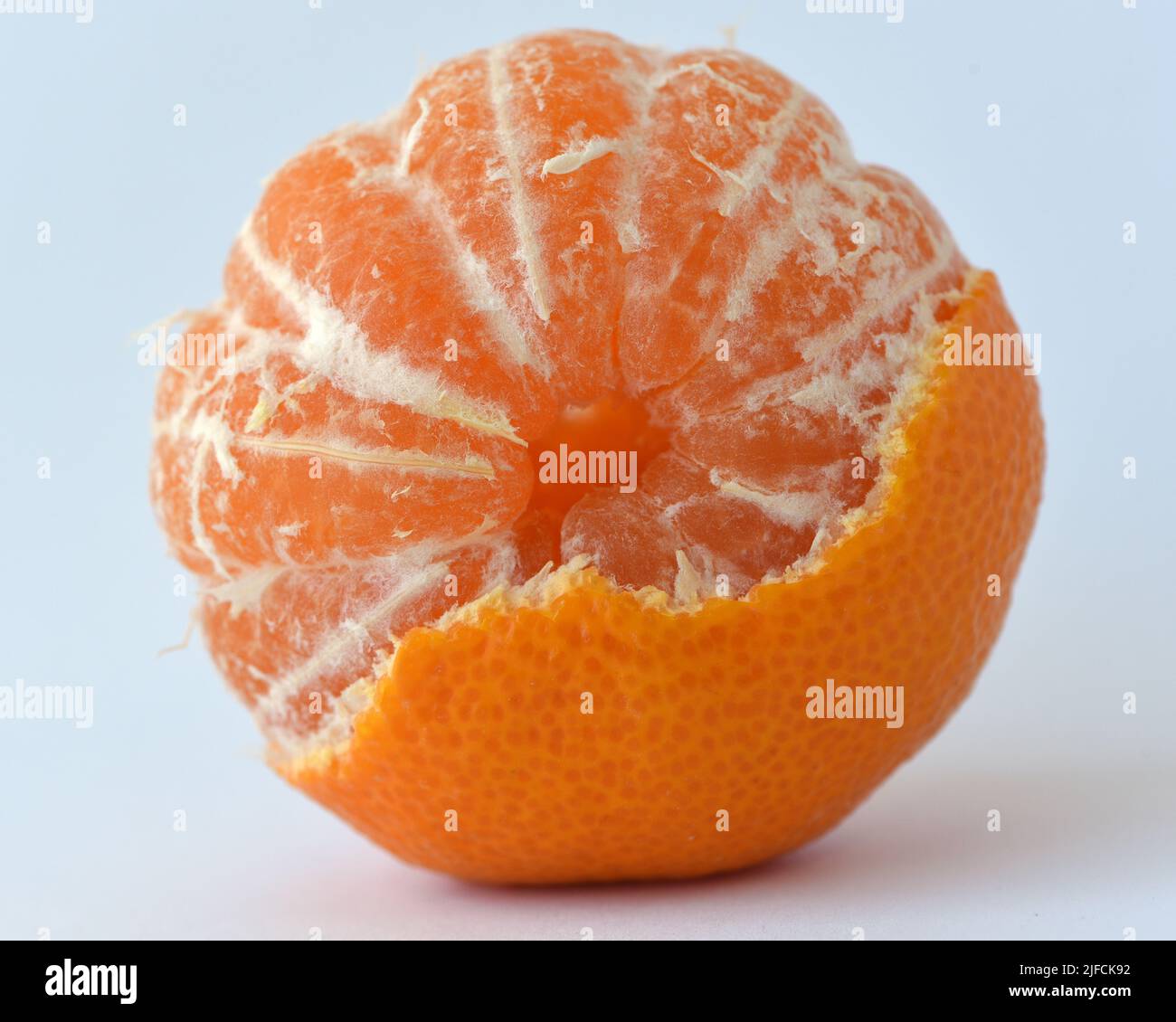 Una vista della parte superiore di un frutto di arancia parzialmente pelato con segmenti visibili Foto Stock