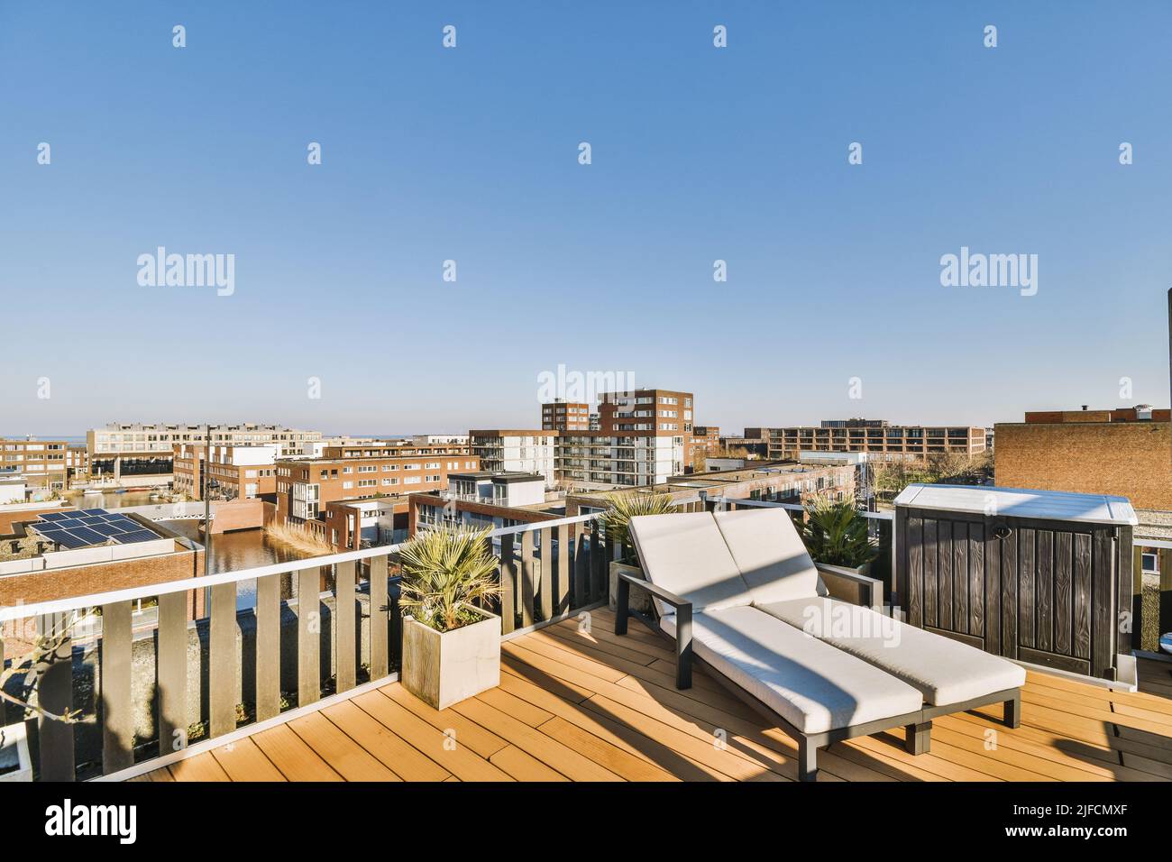 Vista panoramica della città dal tetto di un condominio Vista panoramica della città dal tetto di un condominio con sedie a sdraio in una giornata di sole Foto Stock