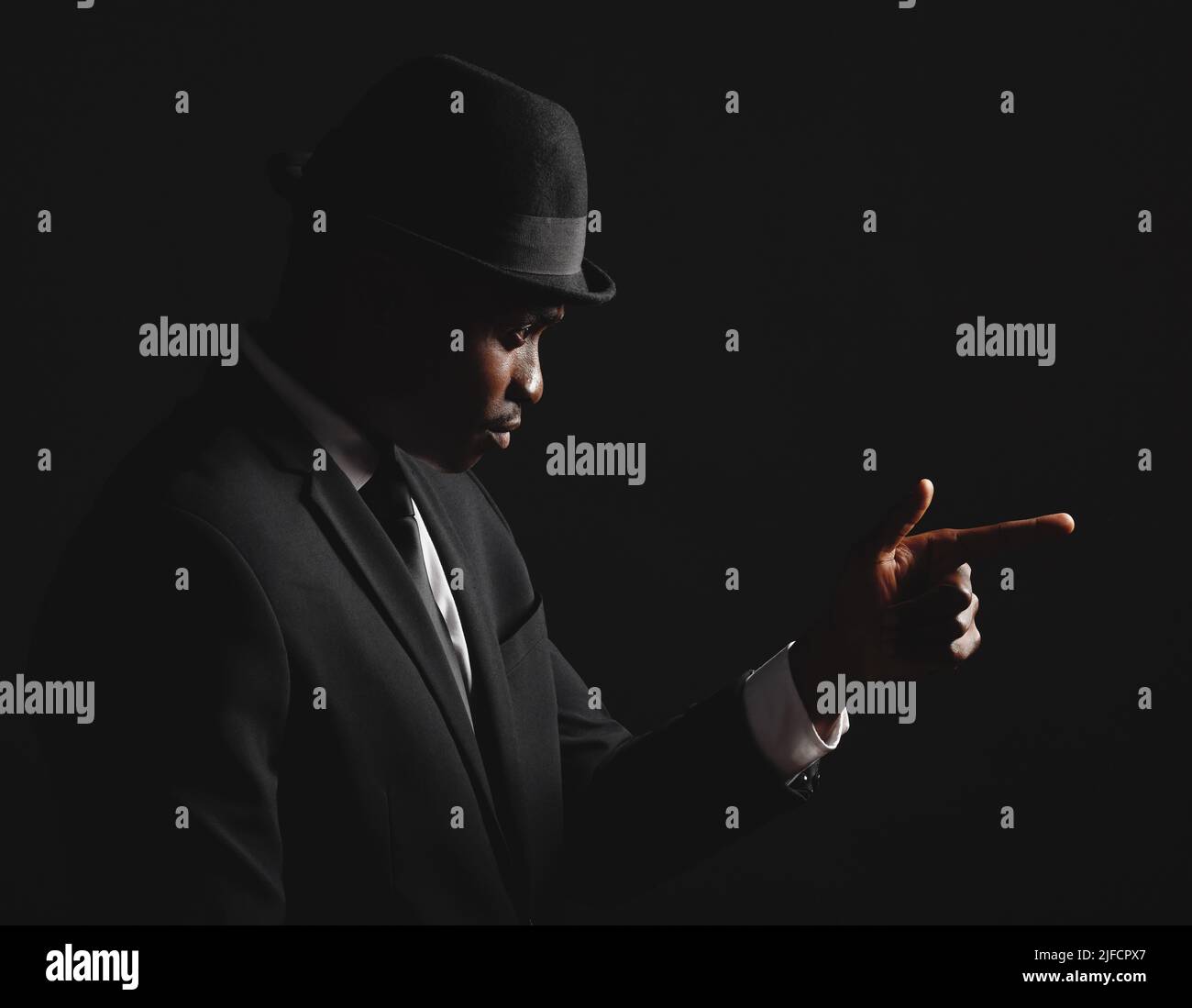 Dapper e giovane uomo fiducioso vestito in abito formale su sfondo scuro. Bell'uomo afroamericano che guarda elegante e sofisticato Foto Stock