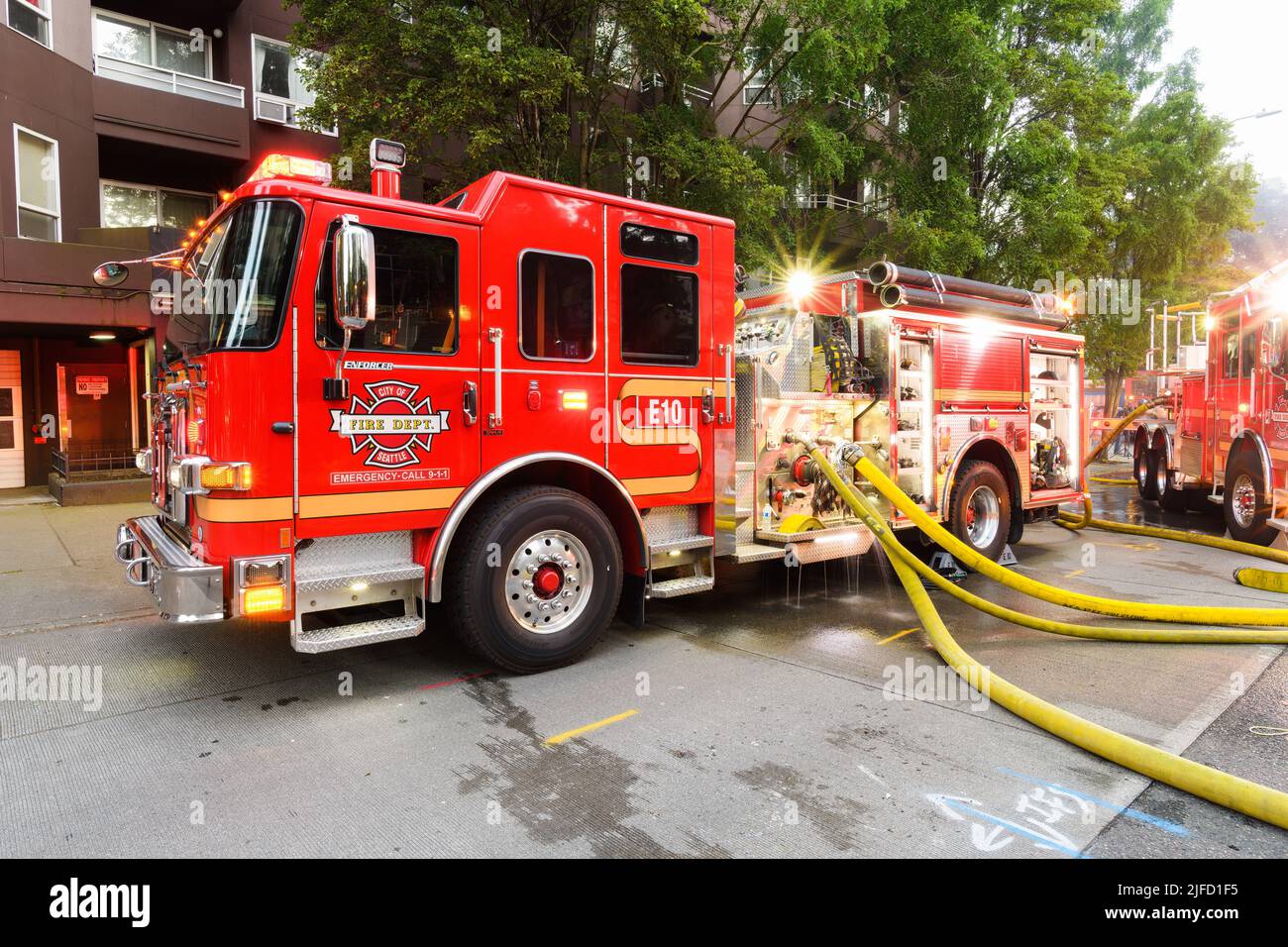 Seattle - 30 giugno 2022; i motori antincendio della città di Seattle che lavorano un incendio attivo a Seattle con tubi gialli pieni attaccati all'apparecchio rosso Foto Stock