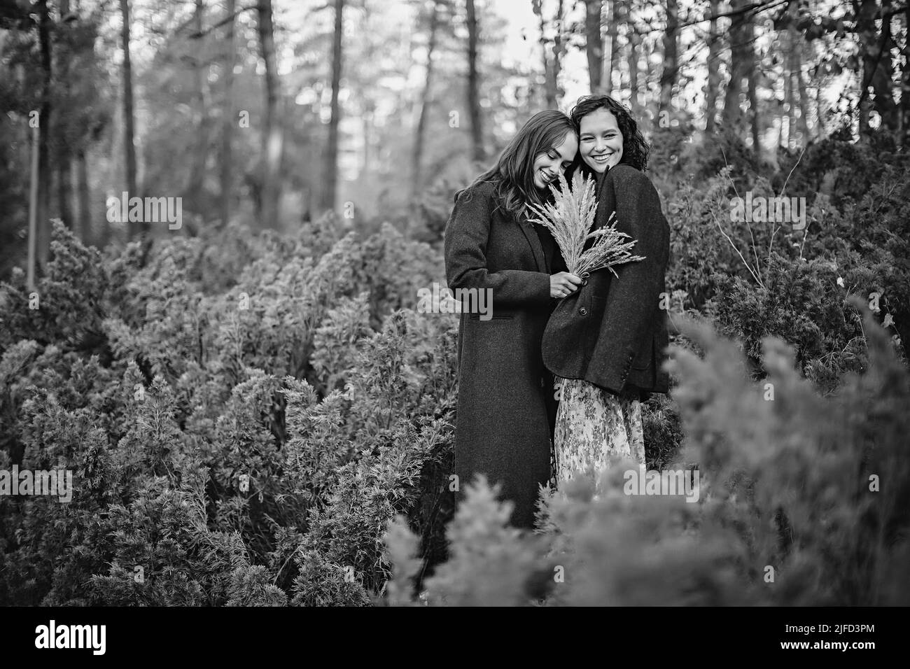 Ritratto bianco e nero di due giovani donne vestite d'epoca che camminano nel parco autunnale Foto Stock
