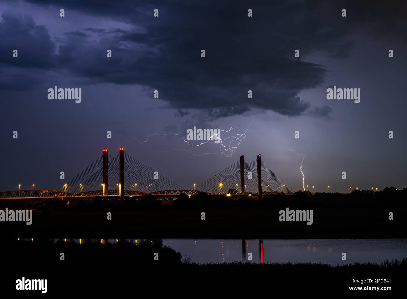Drammatica immagine notturna dei fulmini nei pressi di un ponte sospeso sul fiume Waal nei Paesi Bassi Foto Stock