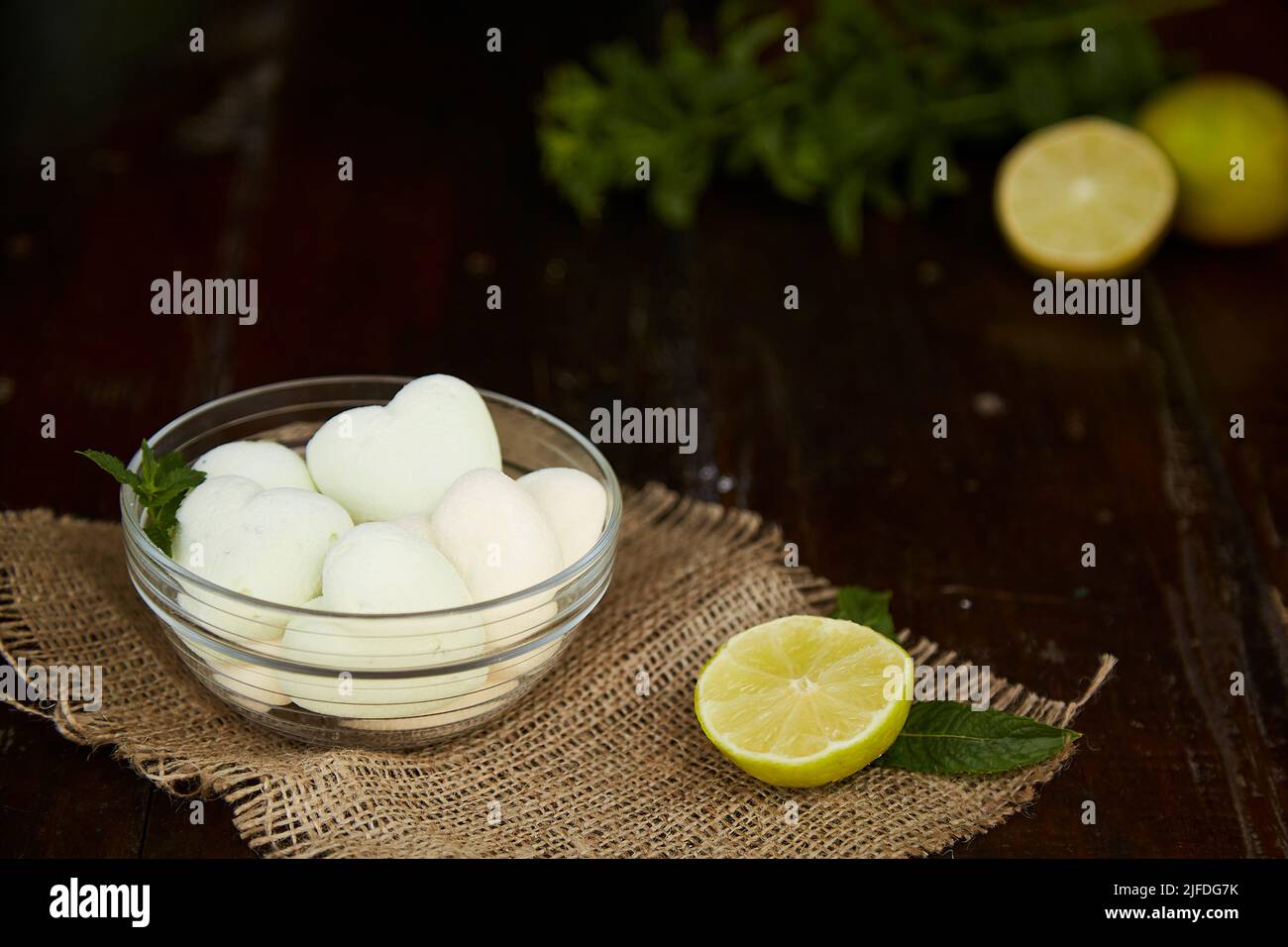 Marshmallows naturali a forma di cuore su insaccamento in pentola di vetro su suzione. Decorazioni in menta e lime. Dolce sano e fresco. Foto Stock