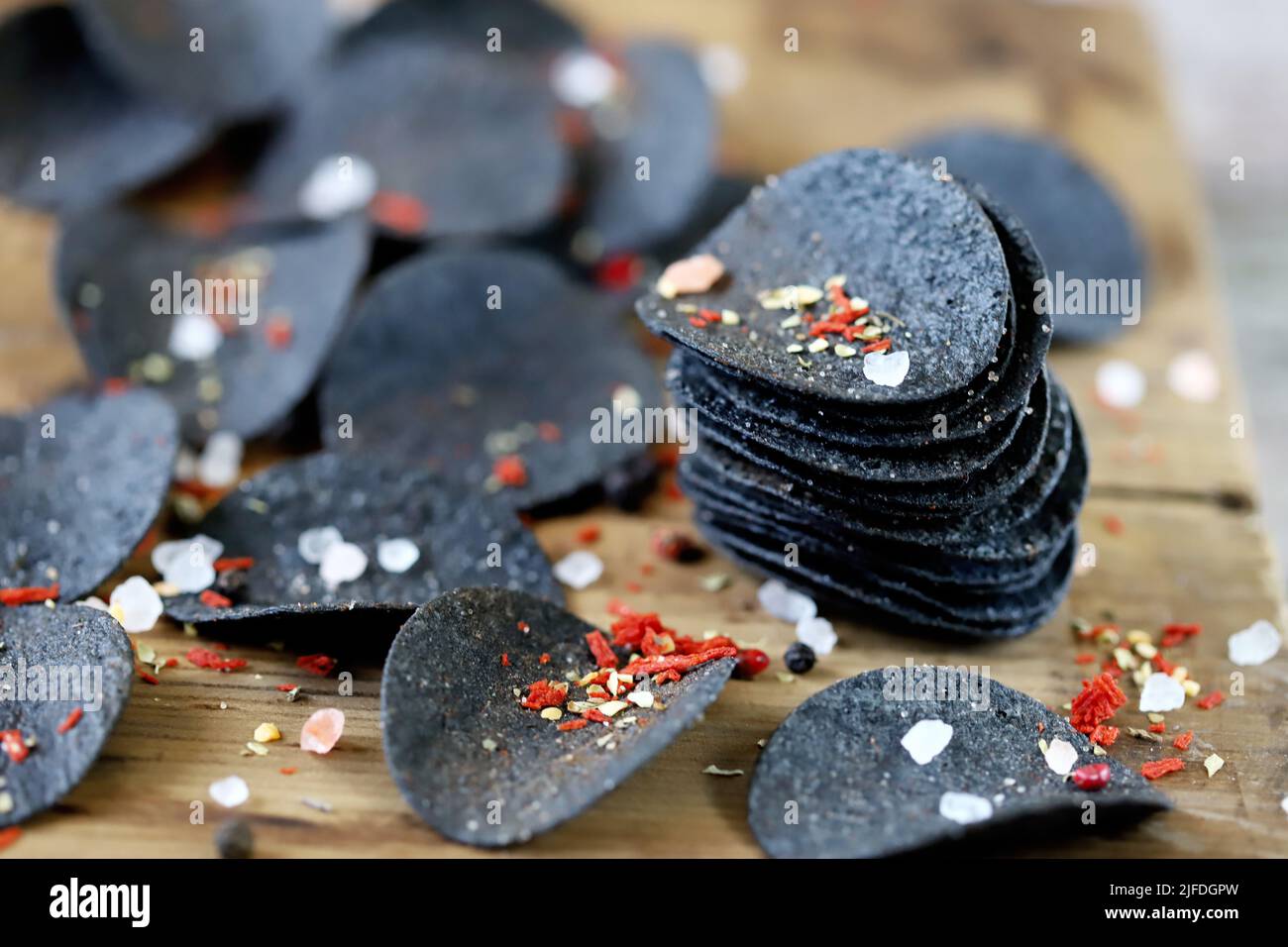 Cibo nero. Patatine nere con spezie su un piatto. Tendenza black food. Seppie inchiostro alimentare. Foto Stock