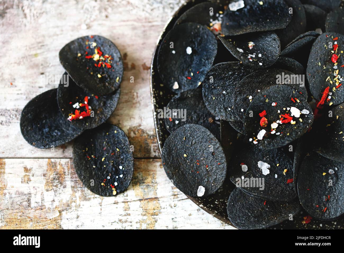Cibo nero. Patatine nere con spezie su un piatto. Tendenza black food. Seppie inchiostro alimentare. Foto Stock