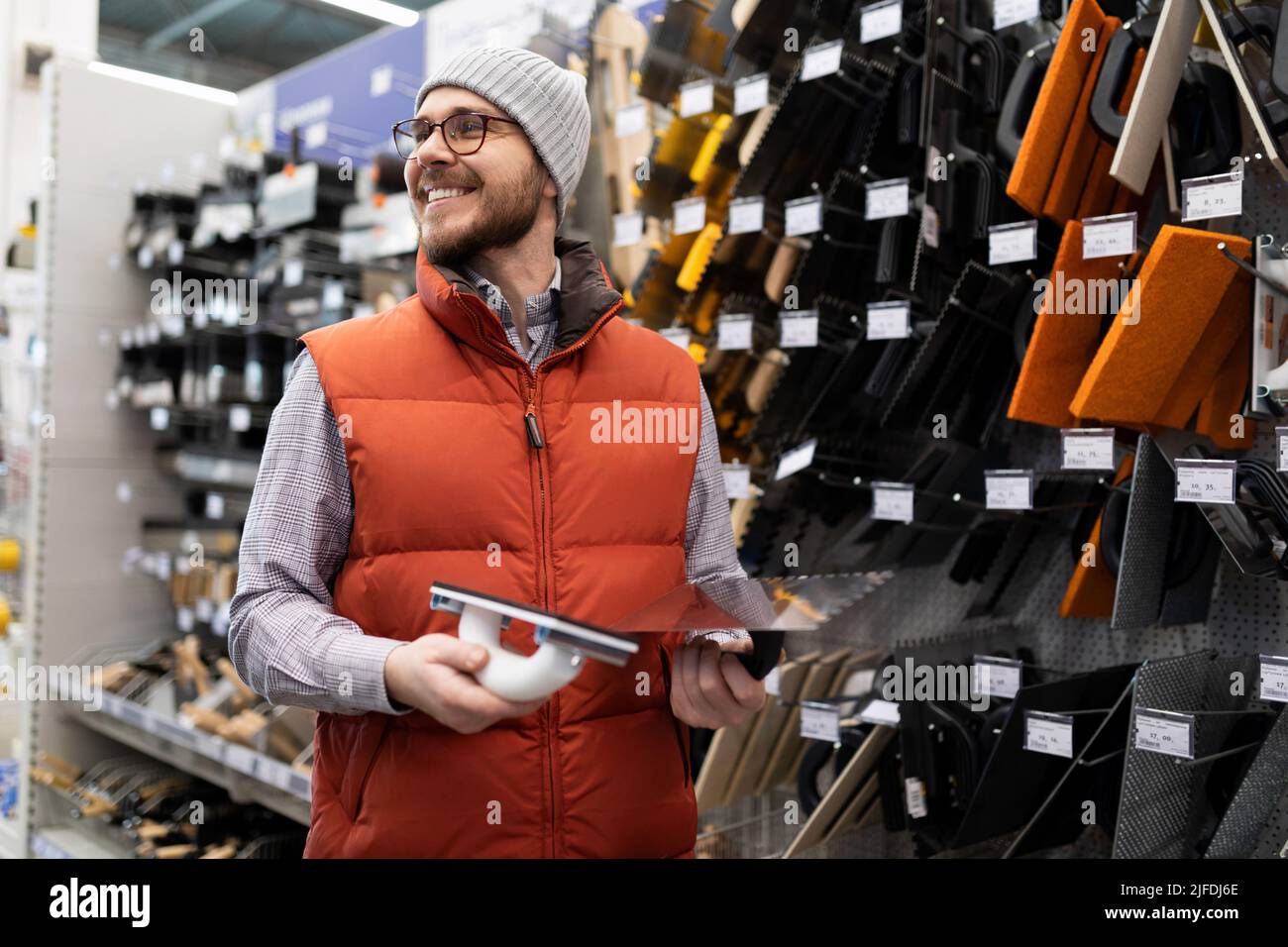 un compratore in un ipermercato di costruzione vicino ad un rack con carta da parati della carta da parati non può decidere su una scelta Foto Stock