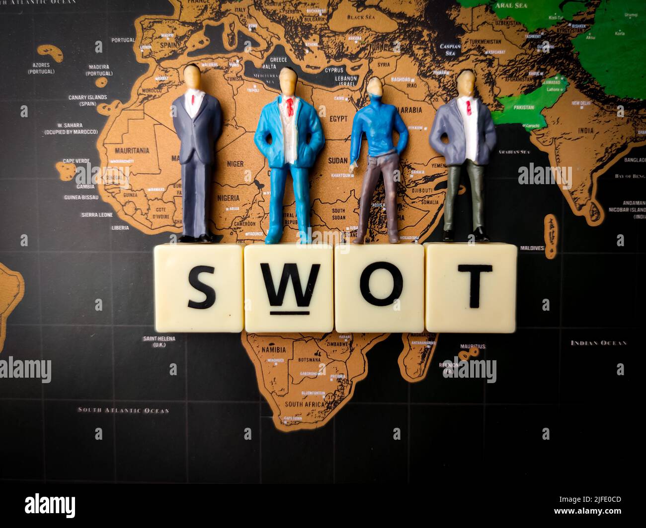 Una vista dall'alto in miniatura di persone e giocattoli con testo SWOT su uno sfondo mappa del mondo Foto Stock