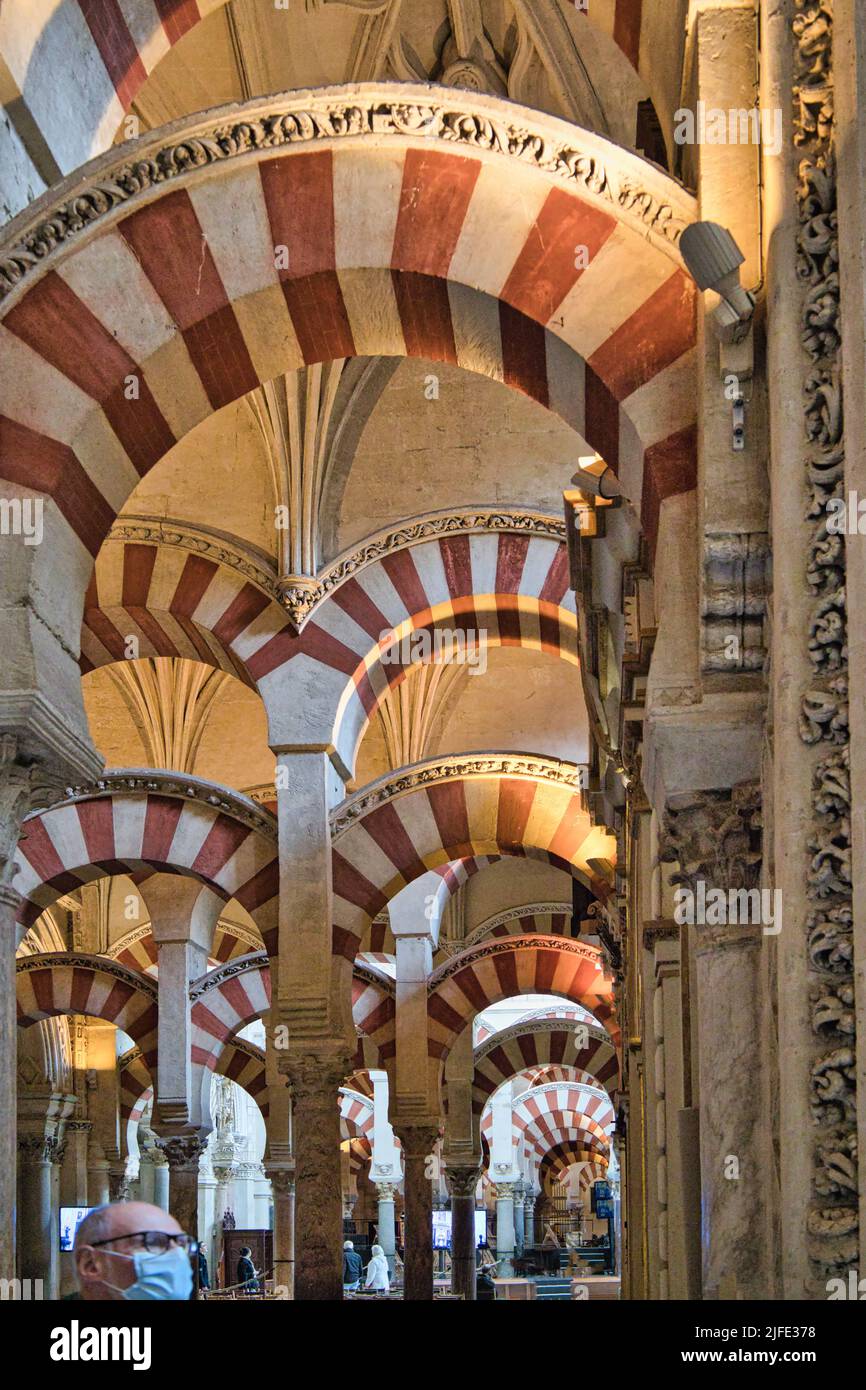 Cordoba, Andalucia, Spagna - persona in maschera esplorando l'interno della Mezquita o la moschea cattedrale con caratteristici archi a doppio livello rossi e bianchi Foto Stock