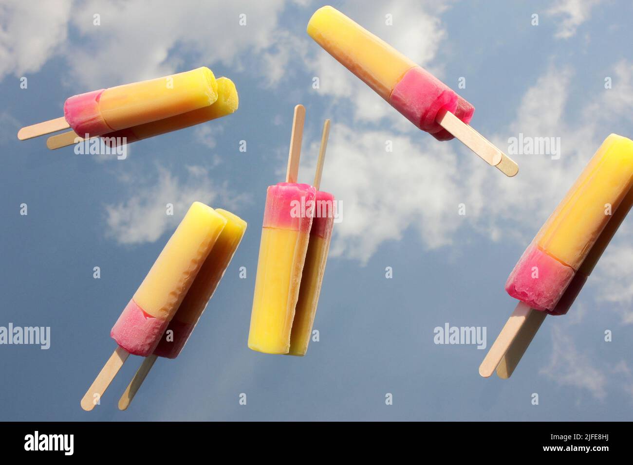 Fondendo il gelato alla frutta su uno sfondo blu cielo. Riflesso del cielo sullo specchio. Concetto estivo. Foto Stock