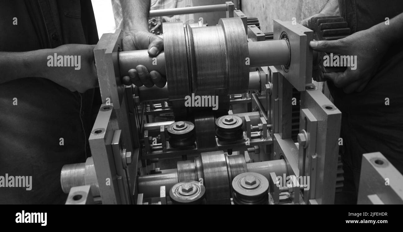 Primo piano di un albero metallico parti che tengono da due persone con le mani del tornio Machinery. Vintage Industrial Machinery in una vecchia fabbrica. Foto Stock