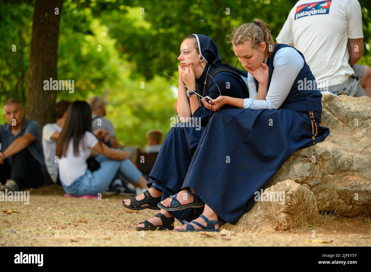 Due giovani monache, tra gli altri pellegrini, ascoltano una catechesi durante il Mladifest 2021 – la festa della gioventù – a Medjugorje. Foto Stock