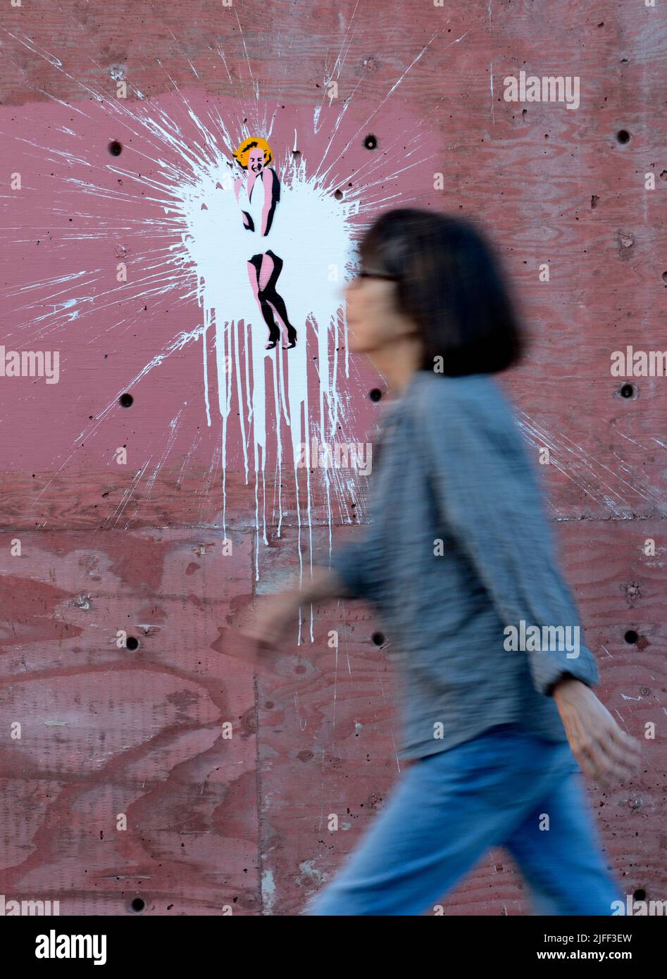 Una donna cammina accanto all'arte di strada su un muro del New Mexico raffigurando Marilyn Monroe in una famosa scena del film "The Seven Year itch". Foto Stock
